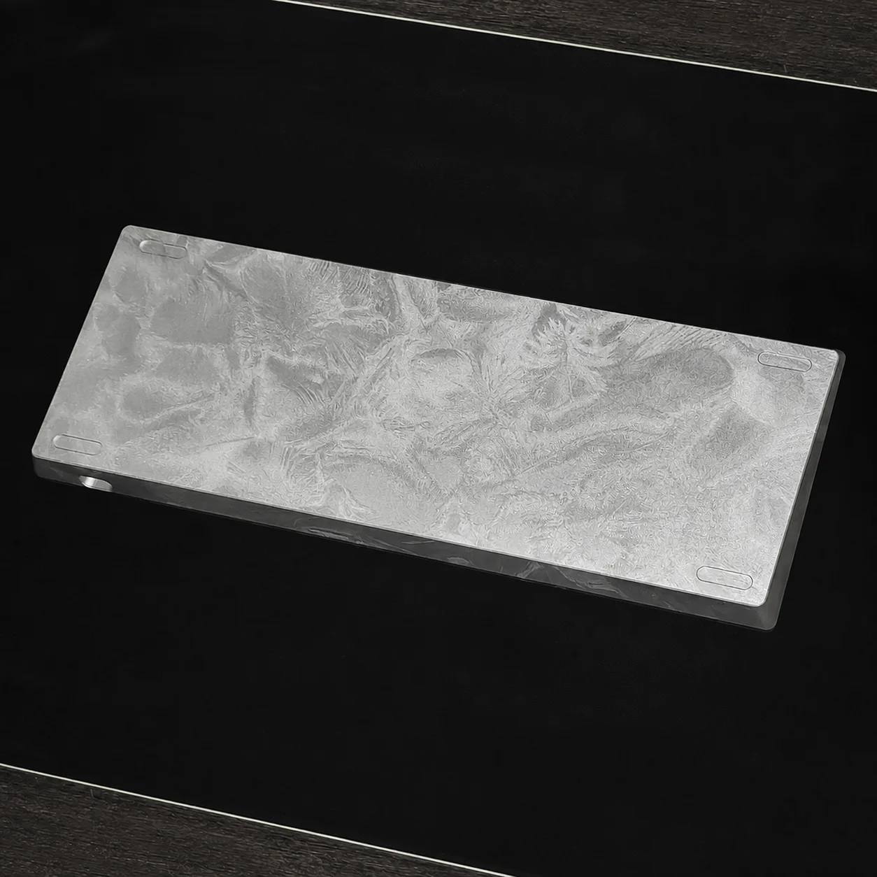 Silver feather-texture aluminum keyboard case on a dark work surface
